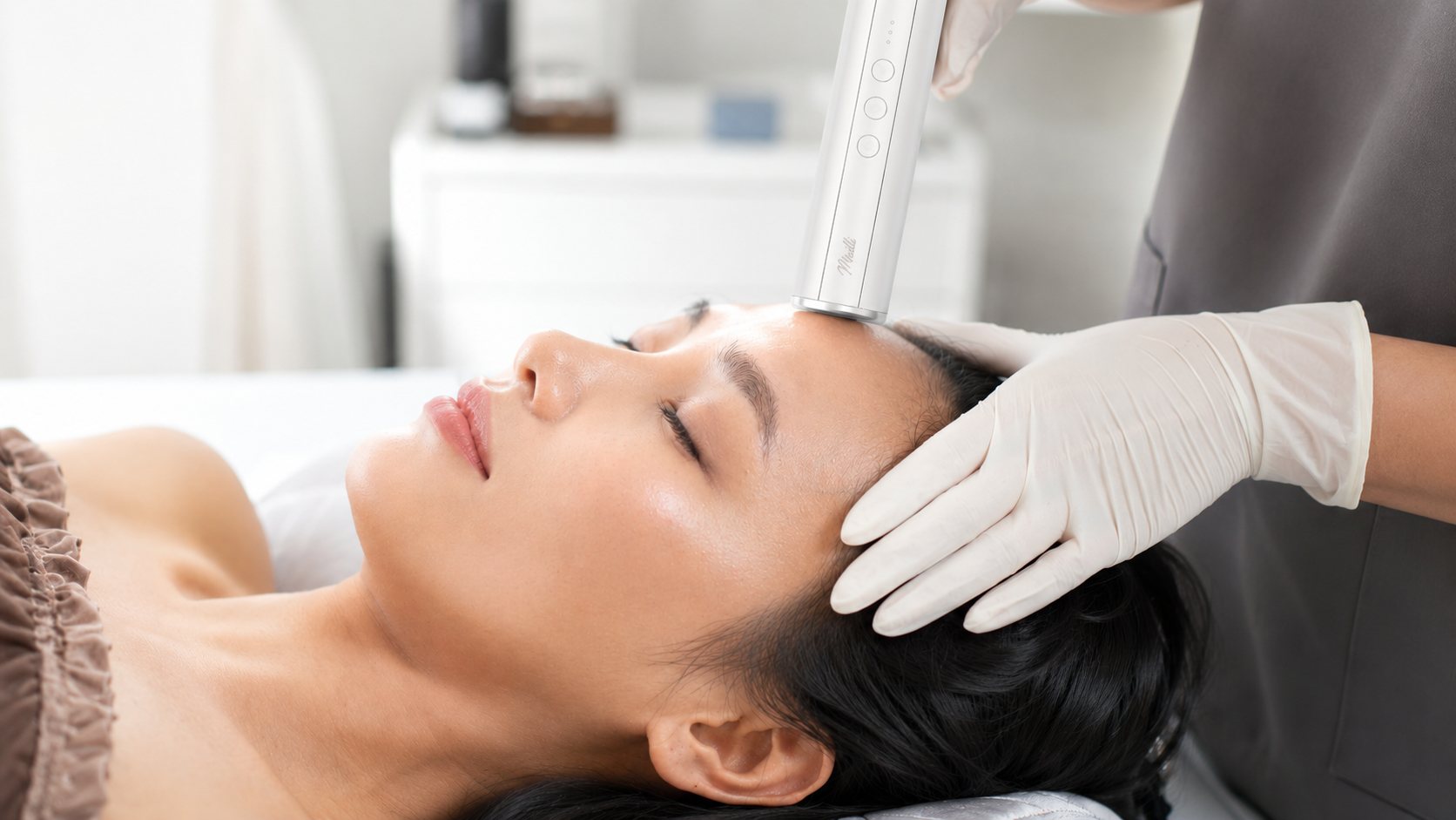 A provider guiding the Muilli dermascope across a client's forehead during a scan